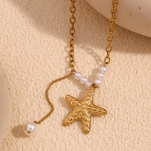 Macro detail of 18K gold starfish pendant with pearls and delicate tassel chain