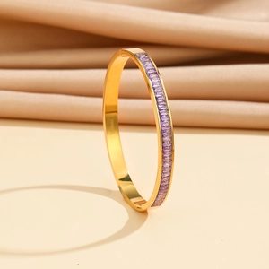Macro detail of gold stainless steel bangle featuring emerald-cut purple zircon stones