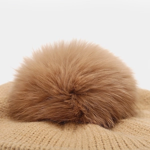 Knitted beret for women with large fluffy pompom and vertical rib texture in camel