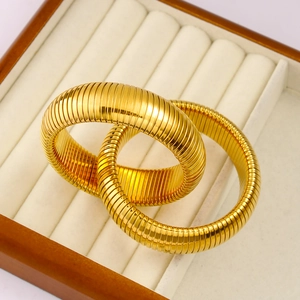 Detail shot of golden spiral tube bracelets inside a premium wooden jewelry case