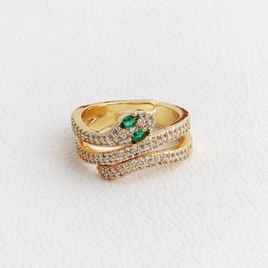 Macro detail of golden snake ring with green stone eyes and white cubic zirconia crystals
