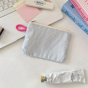 Close-up of light blue jacquard dot storage pouch with pink handle on office desk
