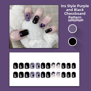 Detail of purple and black checkerboard press-on nails with heart and star patterns