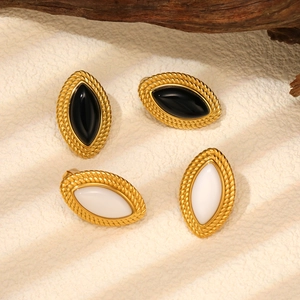 Macro view of vintage marquise-shaped gold earrings with black and white resin inlay