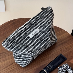 Macro detail of black and white woven tweed makeup bag with simple wish textile label