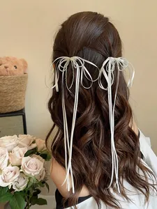 Detailed view of white silk ribbon hair clips with elegant silver bead fringe tassels
