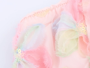 Détail de broderies florales avec paillettes sur couches de tulle rose
