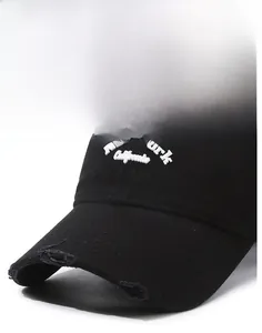 Close-up of vintage black baseball cap featuring white embroidery and distressed ripped brim