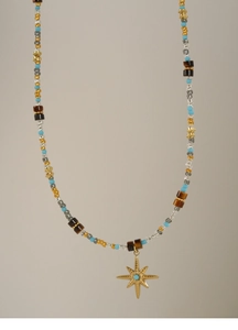 Detail of beaded star necklace featuring tiger eye stones and a gold starburst pendant
