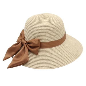 Close-up of beige woven straw hat featuring a detailed coffee brown satin ribbon bow decoration