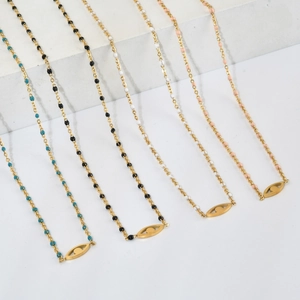 Détail de pendentifs œil en quatre couleurs sur colliers dorés devant pierres