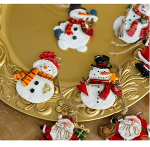 Detailed view of hand-painted resin snowman and Santa hanging ornaments in a gold tray