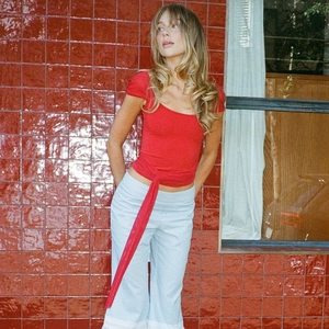Detail of red square neck top with waist ties paired with light blue wide-leg trousers