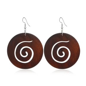 Détail de boucles d'oreilles rondes en bois marron avec motif spirale blanc et crochets
