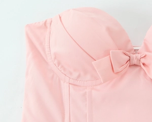 Detailopname van de roze korsettop met een strikje en verfijnde afwerking van naden
