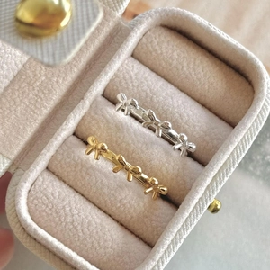 Macro shot of silver and gold bow rings with beaded bands on a velvet jewelry box