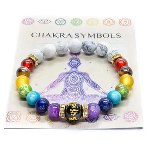 Detail eines 7-Chakra-Natursteinperlenarmbands auf symbolischer Chakra-Karte