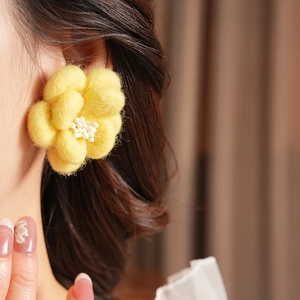Gros plan d'un mannequin portant des boucles d'oreilles fleurs en feutre jaune