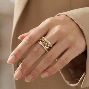 Détail d'une bague chaîne dorée multicouche avec cristaux de zircon sur le doigt d'un modèle