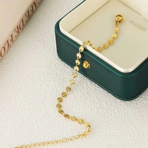 Minimalist gold titanium bracelet with embossed sunburst discs on white textured background