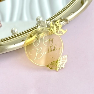 Close-up of golden acrylic Happy Birthday cake topper with hollow butterfly details