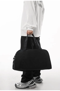 Close-up of a person holding a large black lightweight duffel bag for gym and travel.