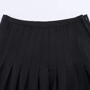 Détail de la jupe plissée noire à taille haute avec coutures précises et fermeture éclair latérale