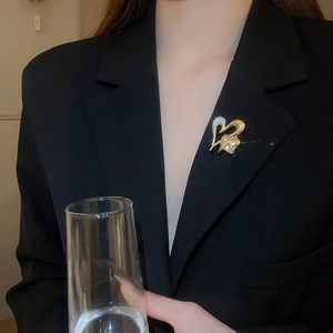 Sparkling diamond-set heart brooch in gold finish on a black suit blazer for women