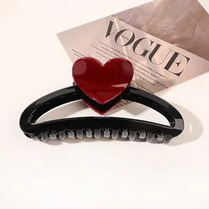 Detail of a large black shark hair claw clip with a glossy red heart on fashion magazine