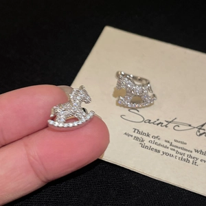 Close-up of sparkling zircon rocking horse clip-on earring with silver finish