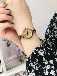 Close-up of small vintage quartz watch with brown leather strap worn by a female model