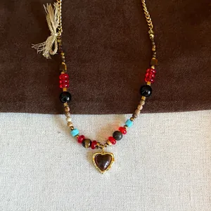 Macro shot of tiger eye stone heart pendant and colorful beads on a gold chain necklace