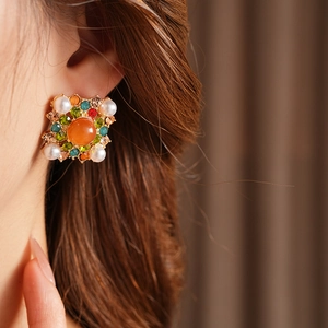 Gros plan détaillé d'une boucle d'oreille vintage avec perle et pierre orange sur un modèle