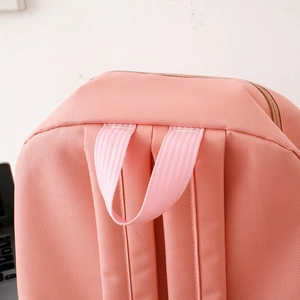 Close-up of pink nylon backpack showing top handle and reinforced stitching detail
