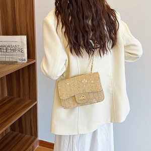 Straw shoulder bag with floral embroidery and golden metal lock for a chic summer look