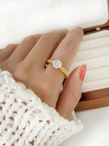 Close-up of golden twisted rope ring with a sparkling round zircon on a model's hand