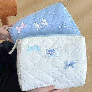 Quilted bow makeup bag in light blue and white featuring macaron colors and ribbon detail