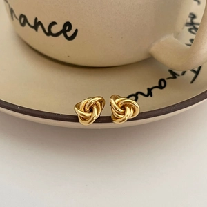 Dettaglio di orecchini a nodo dorati su un piatto di ceramica in un ambiente elegante