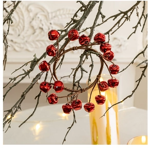 Detail of red Christmas bell wreath hanging on a branch with warm festive lighting