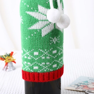 Detail of knitted Christmas wine bottle cover with snowflake pattern and white pom-poms