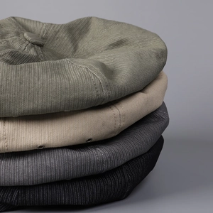 Close-up of stacked corduroy newsboy caps in green, khaki, grey, and black colors
