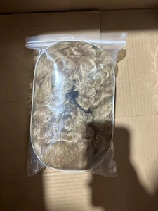 Long wavy blonde wig with bangs packaged in a clear bag for shipping and protection