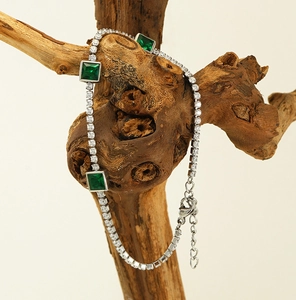 Detail of silver tennis bracelet with emerald square stones and lobster clasp closure