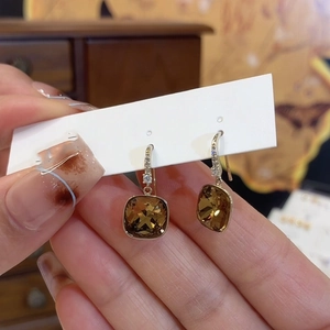 Detail of amber square zircon earrings with gold settings and tiny crystal accents