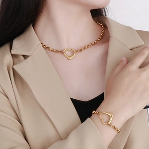 Dettaglio del set collana e bracciale con ciondolo a cuore dorato indossato da modella