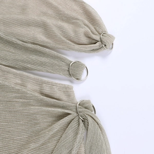 Détail du tissu plissé doré scintillant avec une boucle en métal argenté ronde