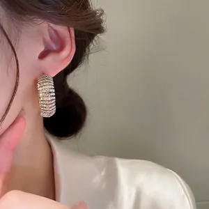 Eleganti orecchini a cerchio a C placcati in oro con pavé di zirconi indossati da modella