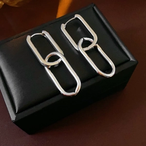 Macro shot of silver oval chain link earrings resting on a black leather jewelry box