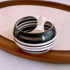 Close-up of vintage black and white striped wide cuff bangle on a wooden tray