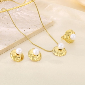 Detailed view of gold plated jewelry set featuring textured discs and white pearls